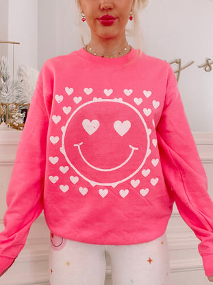 Pink Heart Eyes Crewneck sweatshirt with white smiley face and hearts design.
