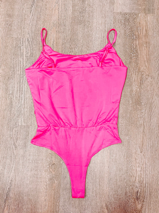 Hot pink bodysuit, back view, shown on wood background.
