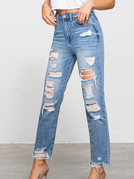 Light wash distressed jeans with frayed hems, shown on a model against a neutral backdrop.
