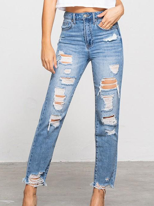 Light wash, distressed denim jeans with frayed hems, shown on a model.
