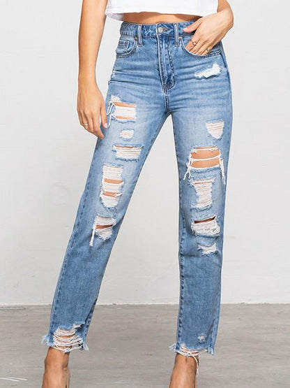 Light wash, distressed denim jeans with frayed hems, shown on a model.
