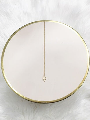 Gold hot air balloon charm necklace on blush pink display.
