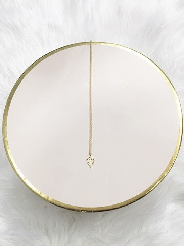 Gold hot air balloon charm necklace on blush pink display.
