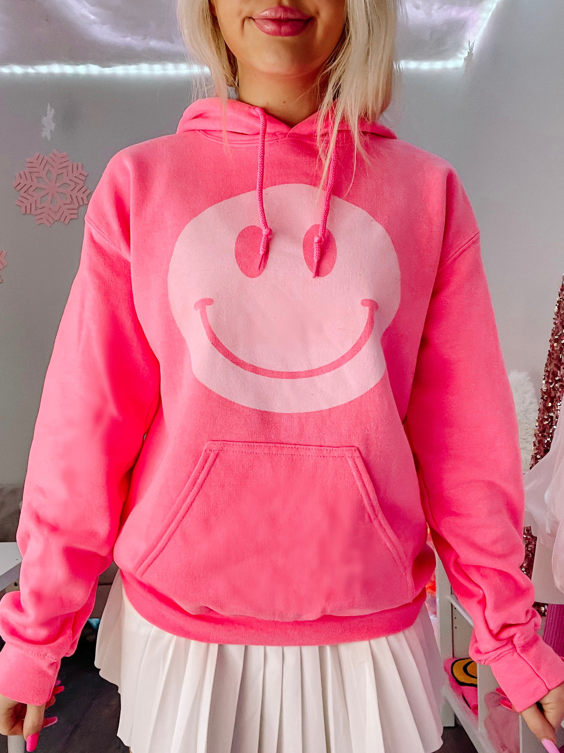 Hot pink hoodie featuring a large white smiley face; comfy, casual style.
