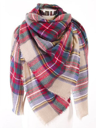 Cozy oversized plaid blanket scarf in red, green, and beige tones, featuring a fringed edge.
