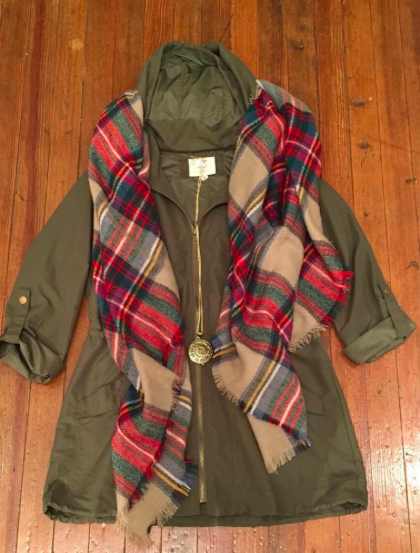 Olive green jacket styled with a red and beige plaid blanket scarf.
