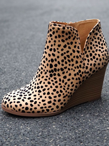 Beige wedge booties with black dalmatian print, shown on dark gray asphalt.
