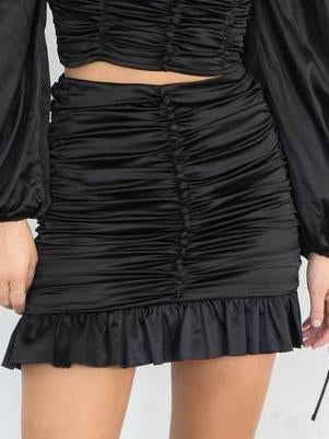 Black mini satin skirt with ruffles, cinched waist.
