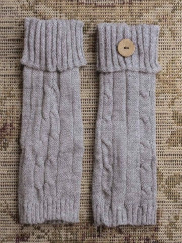 Gray cable-knit cuffs with wooden buttons, displayed on a textured rug.
