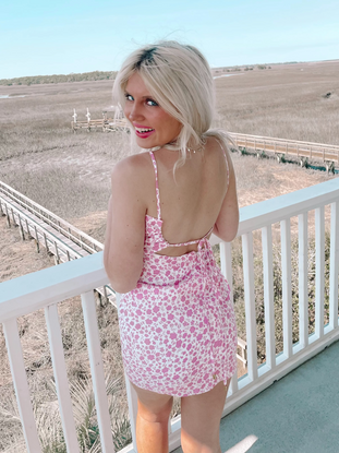 Pink floral mini dress on a porch overlooking a marsh.
