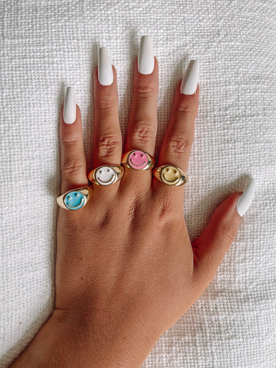Gold smiley face rings with enamel detailing in turquoise, yellow, pink & white.
