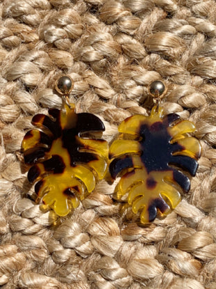 Tortoise shell-patterned resin monstera leaf earrings with gold posts.
