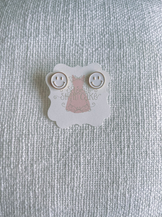 White smiley face stud earrings displayed on a textured white background.