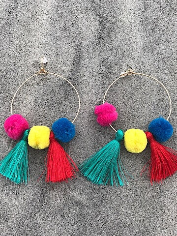 Colorful gold hoop earrings with pink, yellow, & blue pom-poms and tassels.
