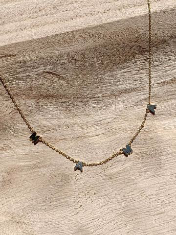 Gold chain necklace with dark gray "MAMA" lettering on light wood background
