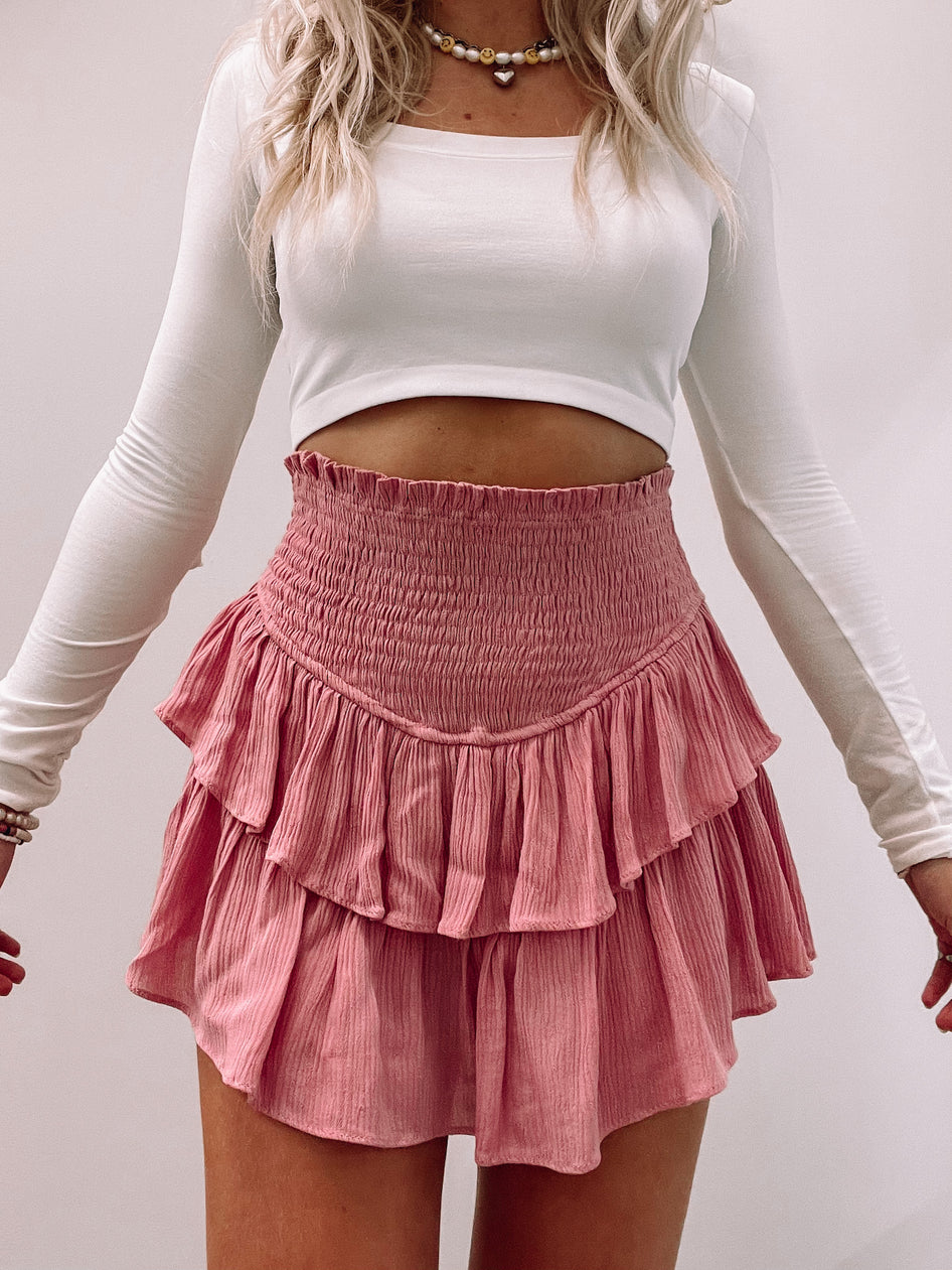 Dusty rose tiered mini skirt with smocked waistband, shown on model.
