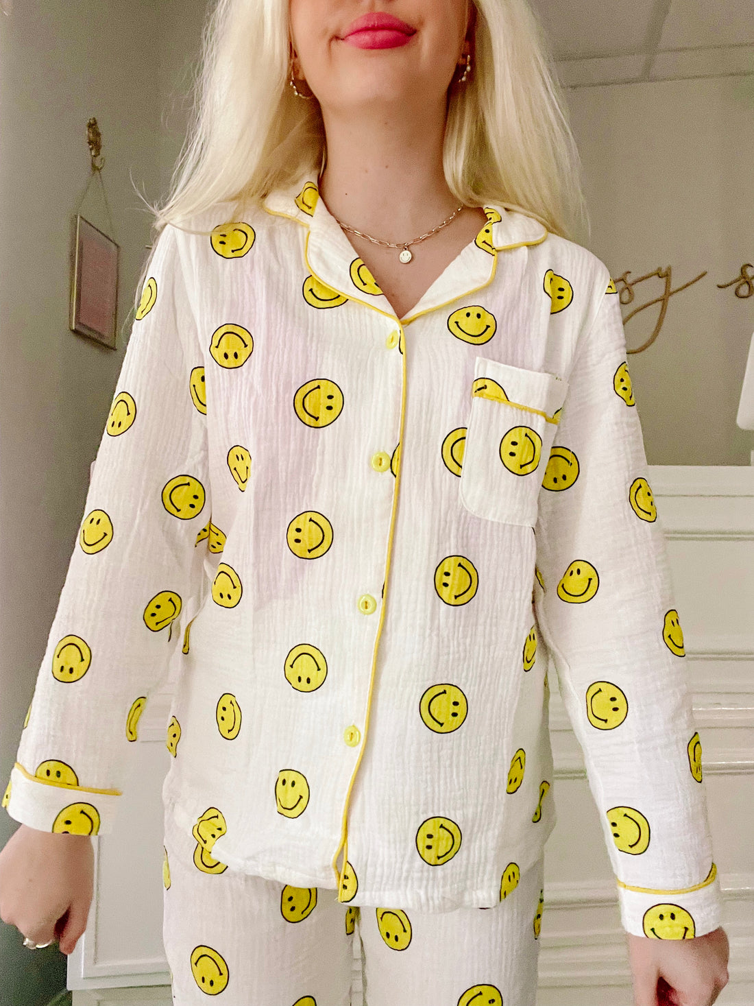 White pajama set with cheerful yellow smiley faces, button-down top and matching pants.
