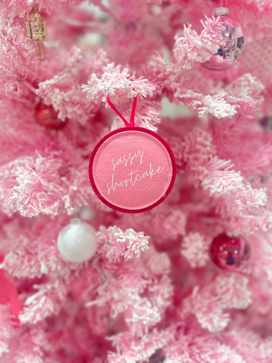 Pink felt Christmas tree ornament with "Sassy Shortcake" in white script.