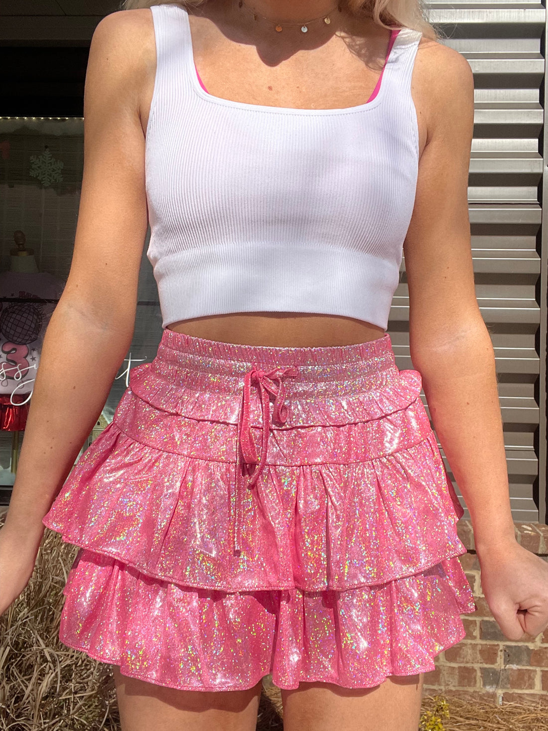 Pink sparkly mini skirt with tiered ruffles, worn outdoors.
