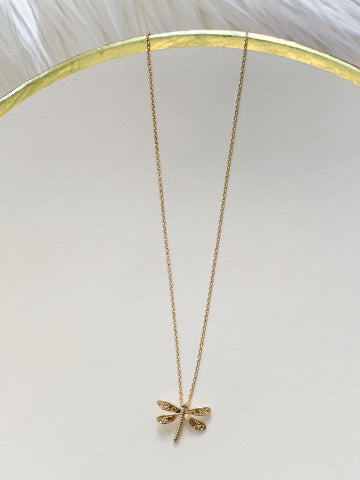 Dainty gold dragonfly pendant necklace on a white background.

