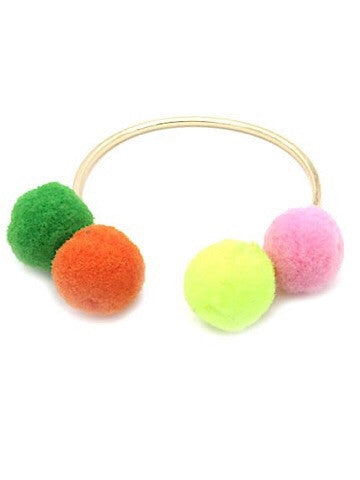 Gold bangle bracelet adorned with three colorful pom-poms.
