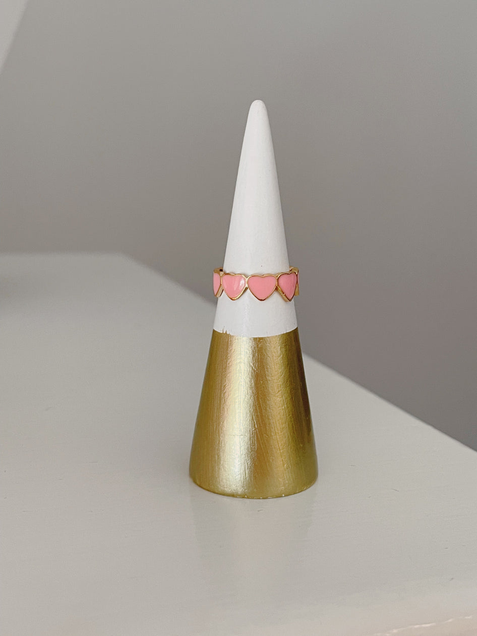 Pink heart ring on gold and white display cone.
