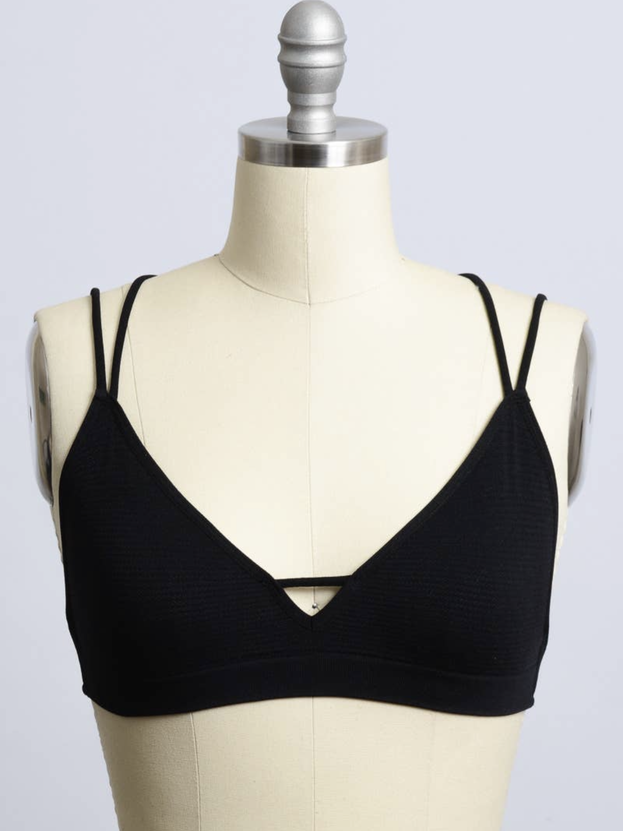 Black bralette with double straps, displayed on a mannequin.
