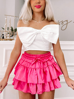 Bows Before Bros hot pink ruffle mini skirt and oversized white bow crop top set
