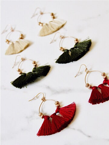 Gold hoop Shimmy & Shake tassel earrings in red, green, and beige.

