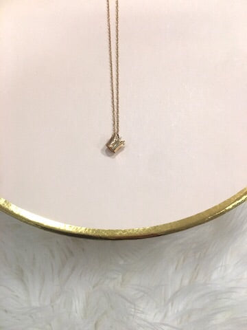 Gold Crown Charm Necklace on pink background
