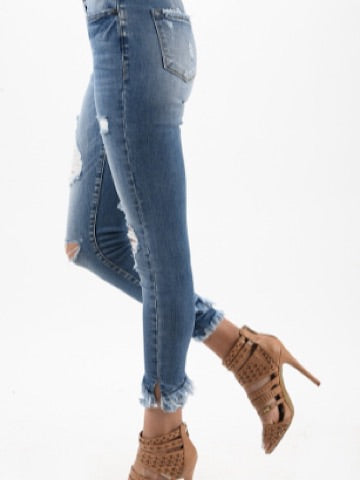 Light wash distressed skinny jeans with frayed hems, shown on a model.
