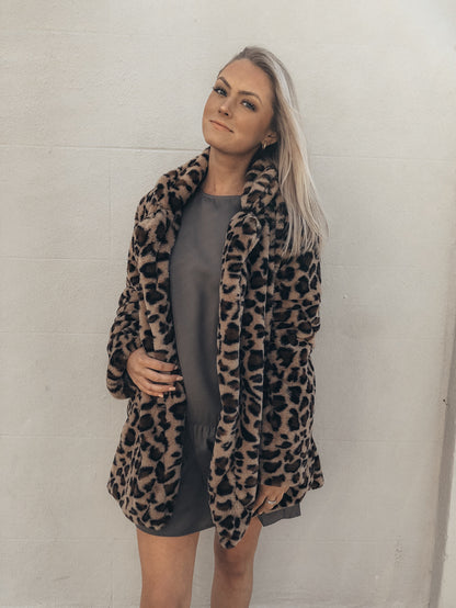 Leopard print faux fur coat styled with a gray mini dress.
