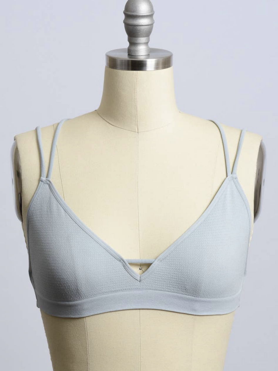 Light blue bralette with double straps, displayed on a dress form.
