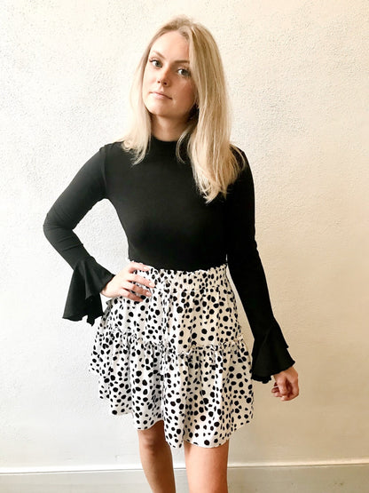 Tiered dalmatian-print mini skirt styled with a black long-sleeve top.
