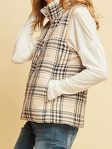 Cream puffer vest with a navy and beige plaid pattern, shown on a model.
