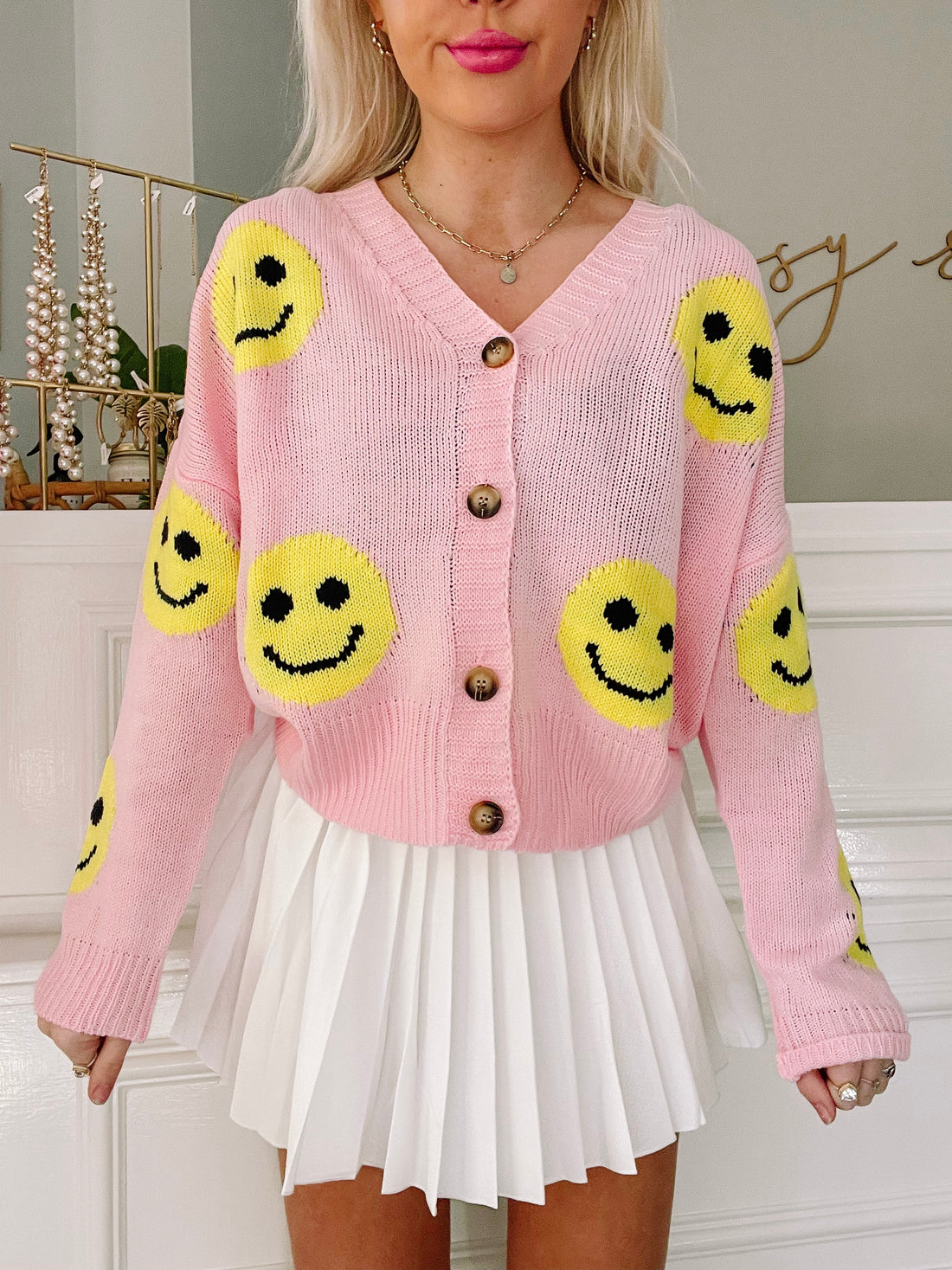 Pink knit Happy Face cardigan featuring yellow smiley faces.
