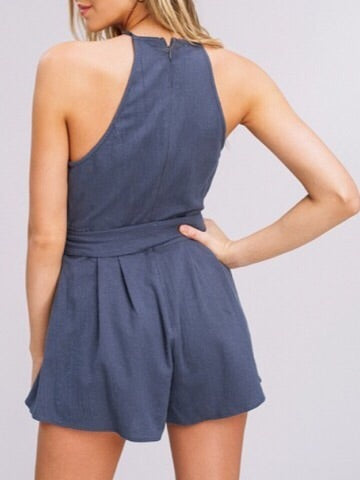 Blue linen romper with halter neck and belted waist.
