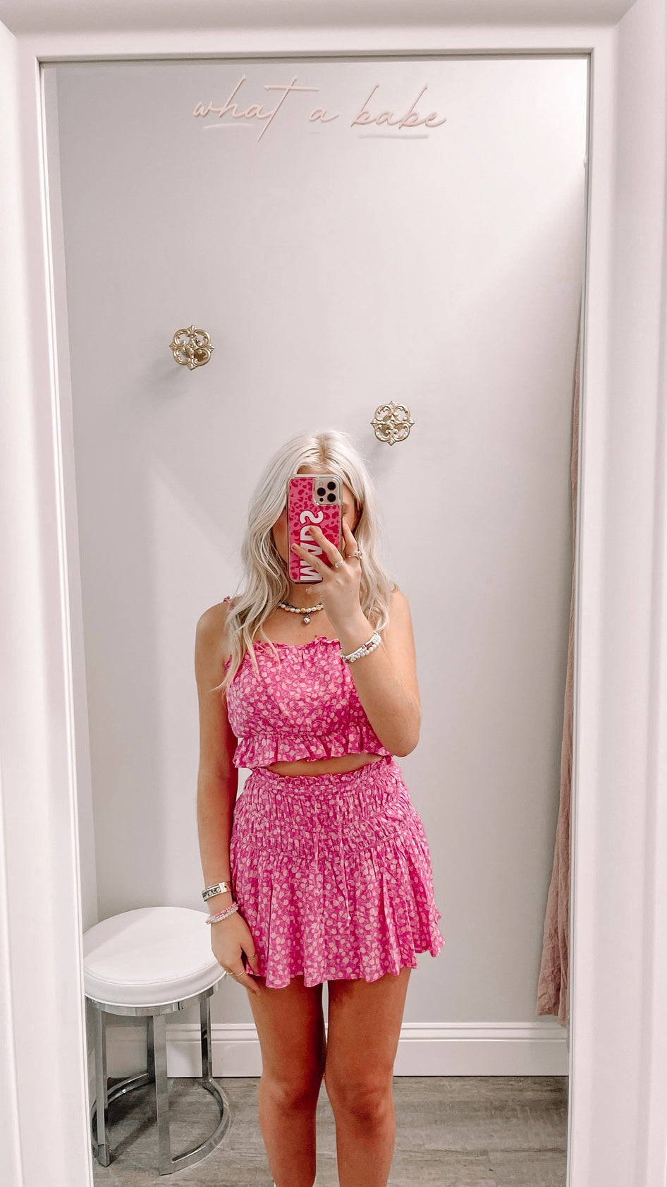 Pink floral print mini skirt and matching crop top, styled in a bright fitting room.
