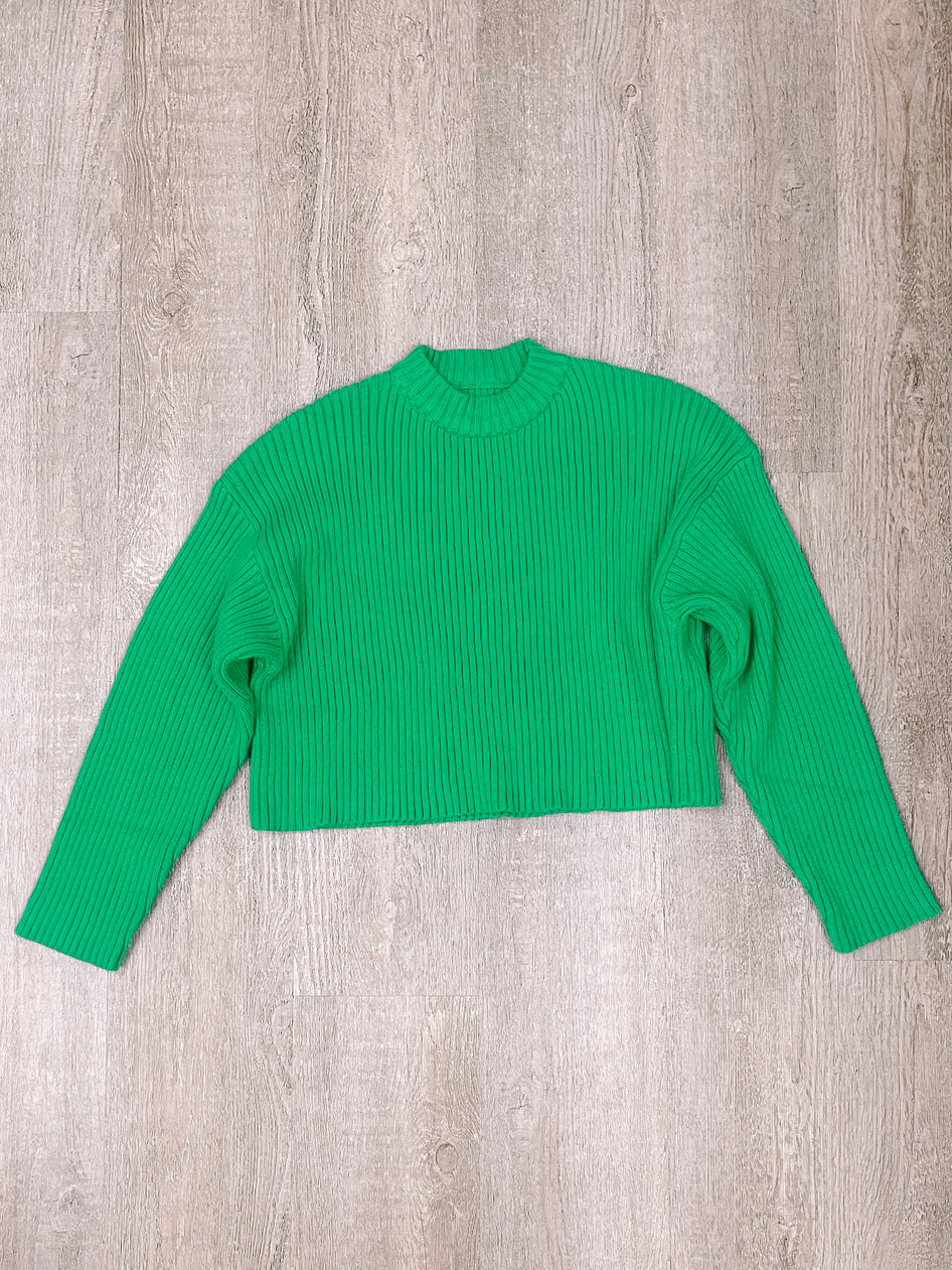 Bright green ribbed knit cropped sweater displayed on woodgrain background
