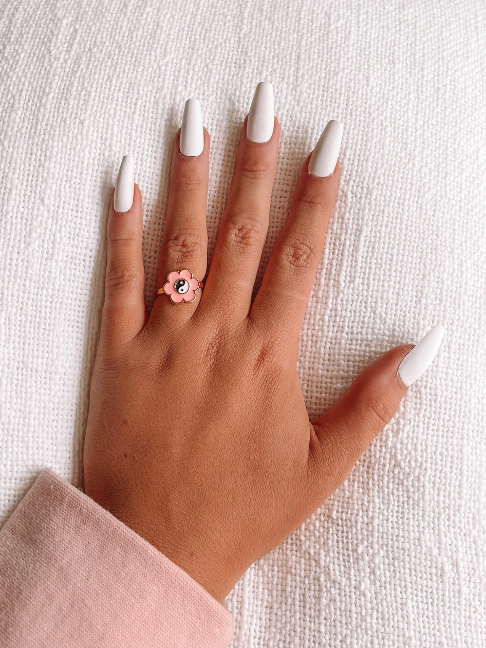Ring Rang Ring: Gold ring featuring a pink flower with a yin-yang symbol.
