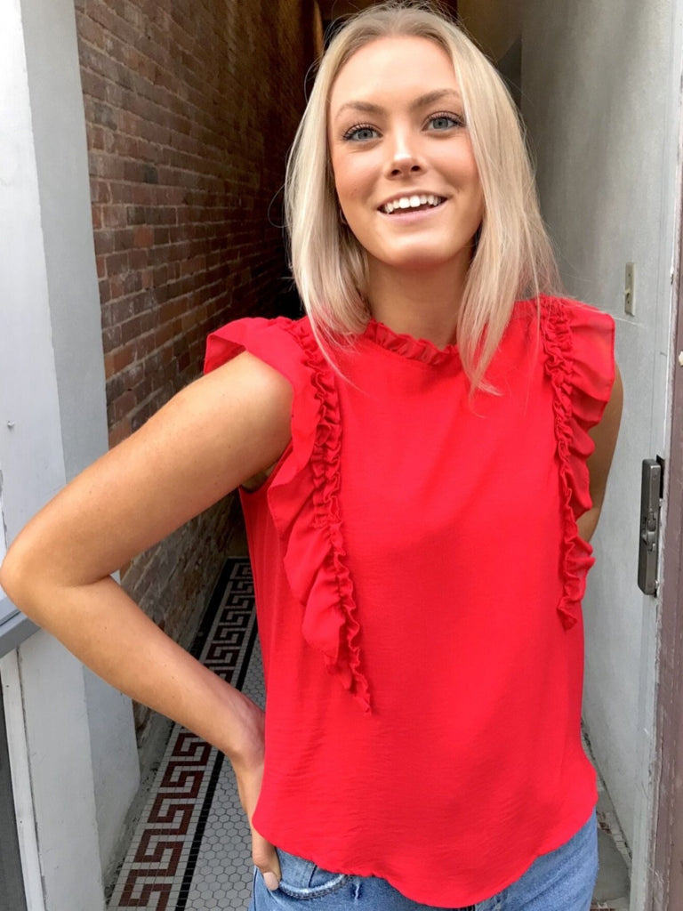 Red ruffle-trimmed blouse, modeled outdoors.
