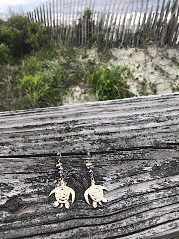 Gold sea turtle earrings with blue beads, beach-inspired dangle design.
