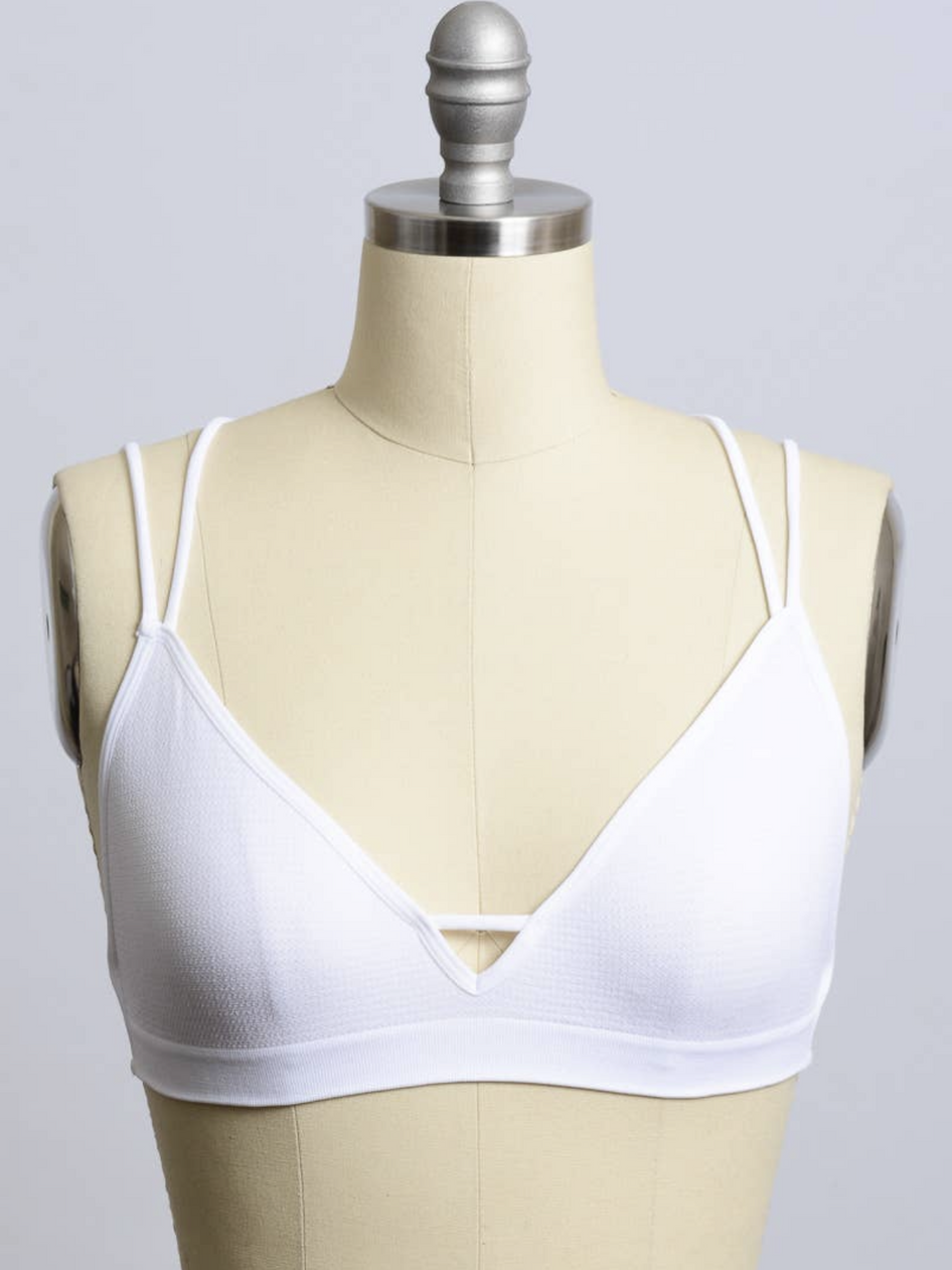 White bralette with double straps on a dress form, against a neutral background.
