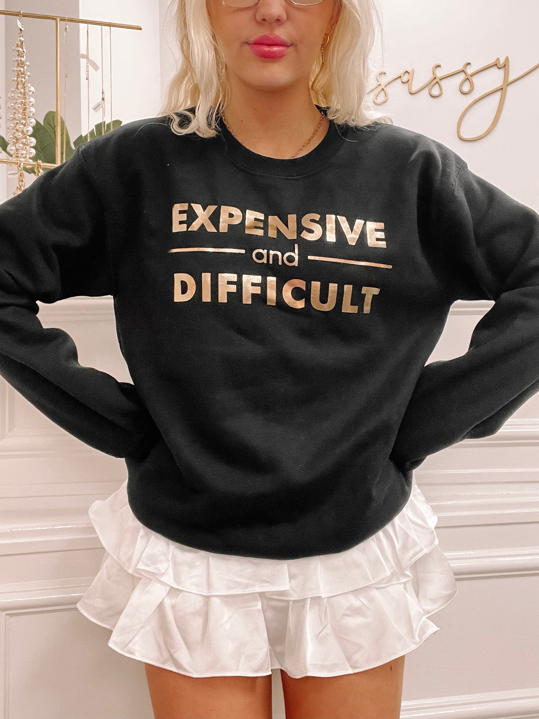 Black crewneck sweatshirt with gold "Expensive and Difficult" text.
