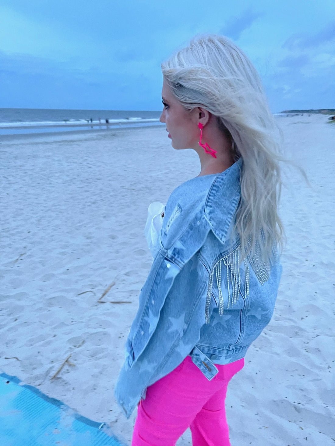 Light wash denim jacket with star accents, worn on a beach.
