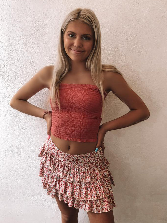 Floral mini skirt with tiered ruffles, worn with a coral top.
