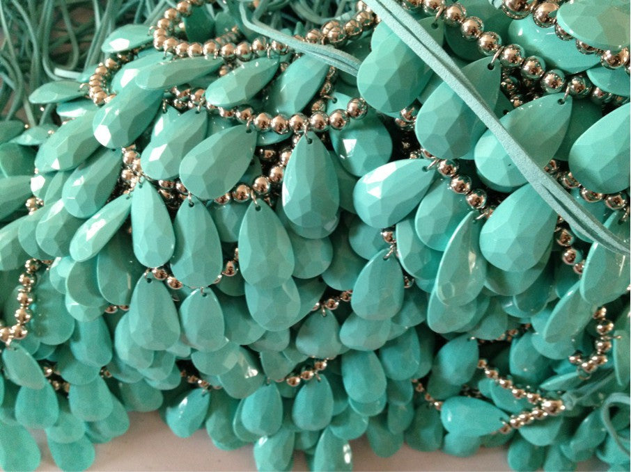 Teal teardrop pendant necklace with silver beads, close-up view.
