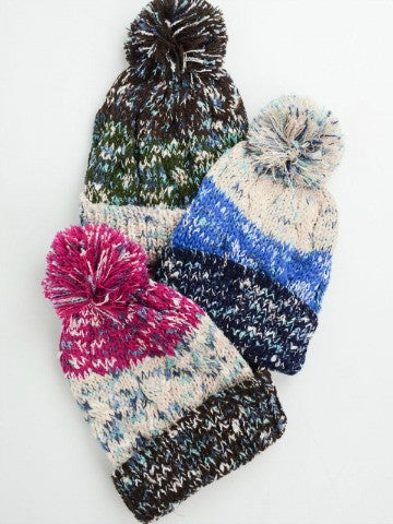Cozy knit beanies with colorful pom-poms, featuring a striped pattern.
