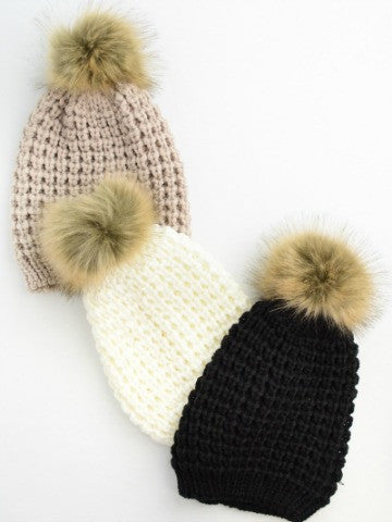 Poof Beanie: Cozy knit beanie with fluffy pompom, available in beige, cream, and black.
