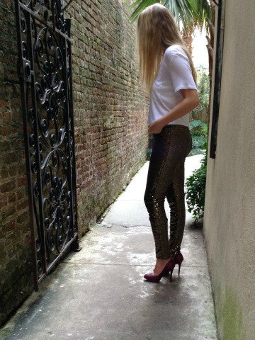 Sequin leggings in gold, worn with heels in a brick alleyway.
